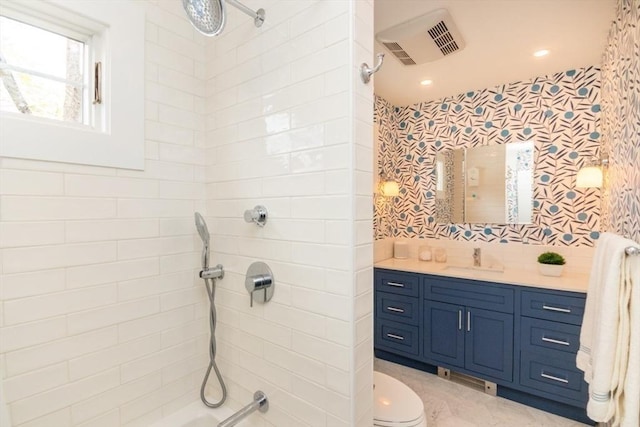 bathroom with toilet, visible vents, tiled shower, and vanity
