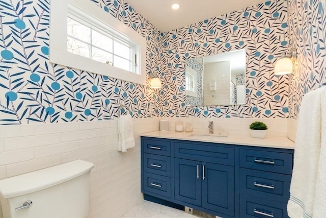 bathroom with vanity, toilet, and wallpapered walls
