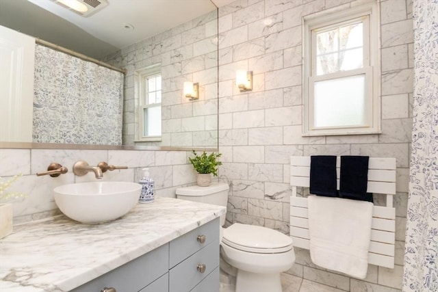bathroom with vanity, toilet, a shower with shower curtain, tile walls, and visible vents