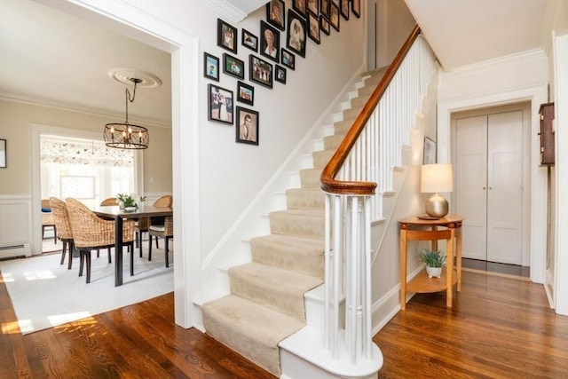stairway featuring crown molding, wood finished floors, and a notable chandelier