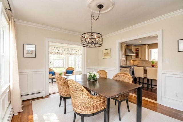 dining room with light wood-style floors, a baseboard radiator, a decorative wall, and a chandelier