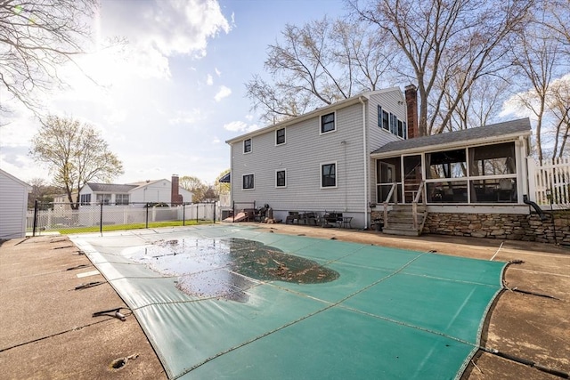 view of swimming pool with a sunroom and fence