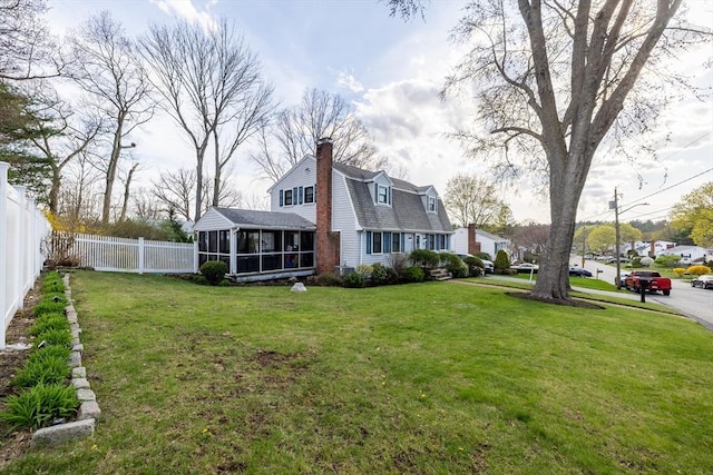 rear view of property with fence, a chimney, a sunroom, a shingled roof, and a lawn