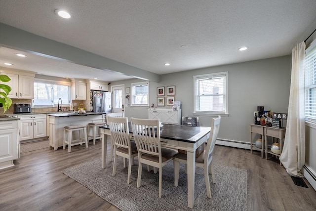 dining area with a baseboard heating unit, recessed lighting, and wood finished floors