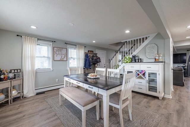 dining space with light wood-type flooring, recessed lighting, a textured ceiling, and stairway
