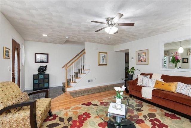 living area with wood finished floors, stairs, ceiling fan, and healthy amount of natural light