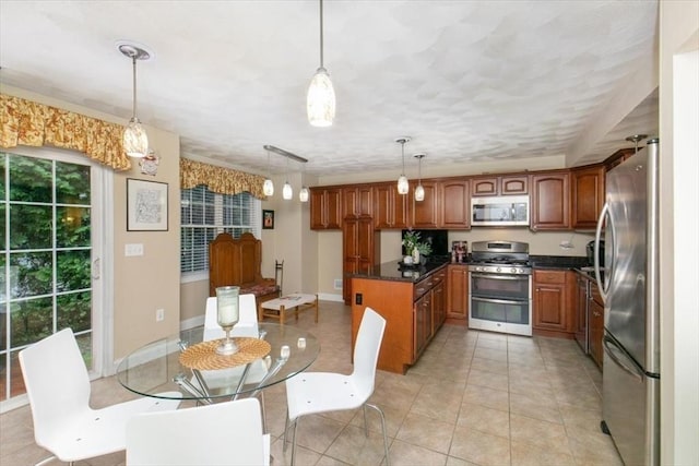 kitchen with appliances with stainless steel finishes, brown cabinetry, hanging light fixtures, and light tile patterned floors