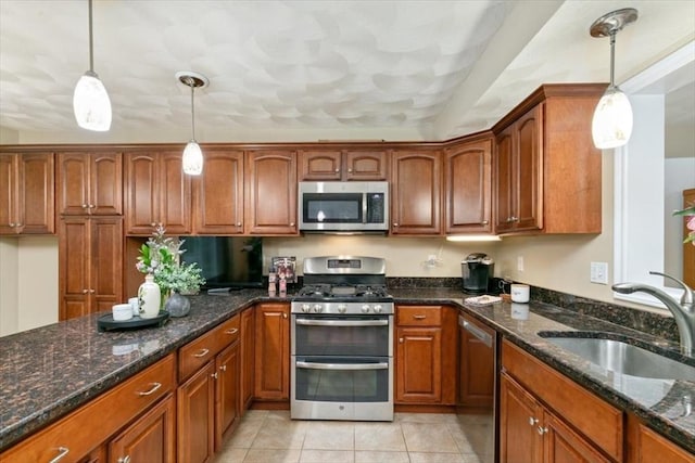 kitchen with stainless steel appliances, a sink, brown cabinetry, and dark stone counters