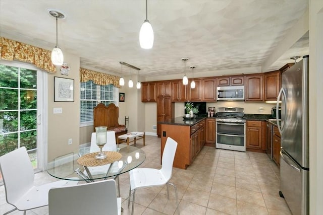 kitchen featuring appliances with stainless steel finishes, brown cabinetry, hanging light fixtures, and light tile patterned flooring