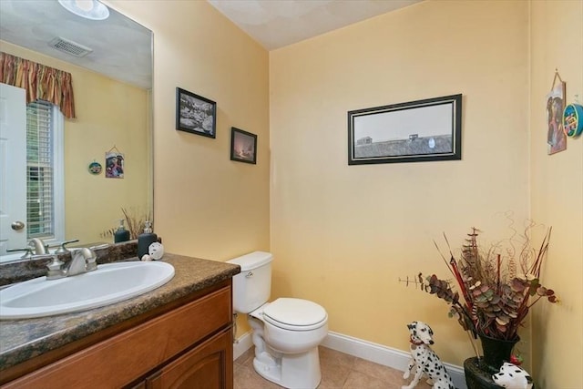bathroom featuring toilet, vanity, tile patterned floors, and baseboards