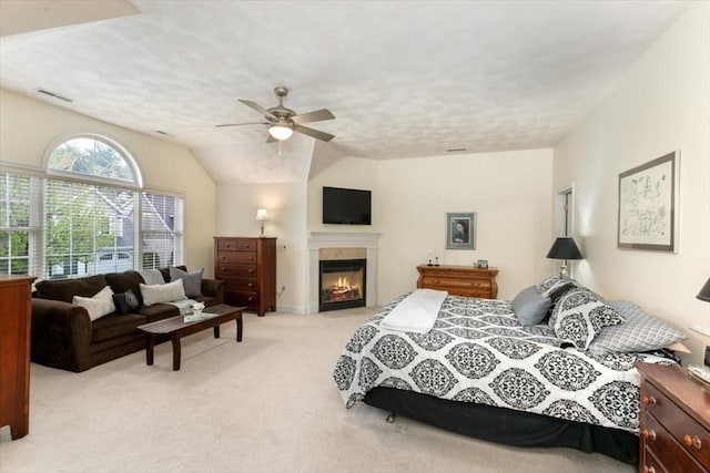bedroom with light carpet, a glass covered fireplace, ceiling fan, and lofted ceiling