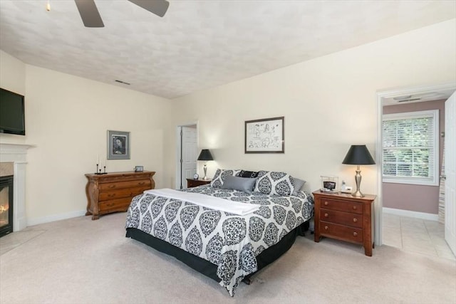 bedroom with light colored carpet, a premium fireplace, baseboards, ceiling fan, and a textured ceiling
