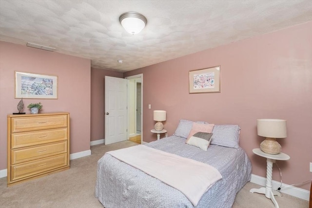 bedroom featuring baseboards, light carpet, and a textured ceiling