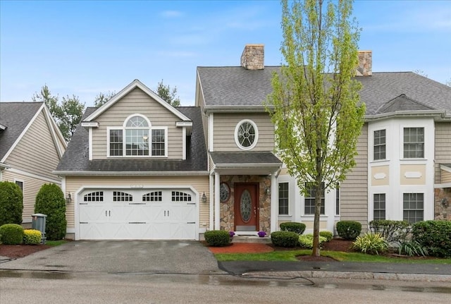 view of front of house featuring asphalt driveway, an attached garage, a chimney, a shingled roof, and stone siding