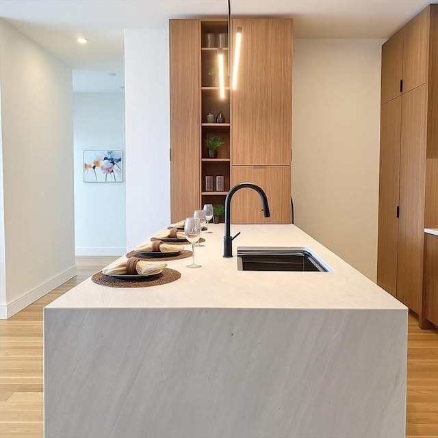 58 Kent St Unit 404, Brookline, MA 02445 - kitchen featuring modern cabinets, a sink, light wood-type flooring, a kitchen island with sink, and recessed lighting