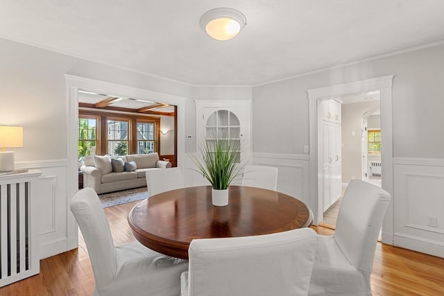 dining room featuring a decorative wall, healthy amount of natural light, light wood finished floors, a wainscoted wall, and ornamental molding