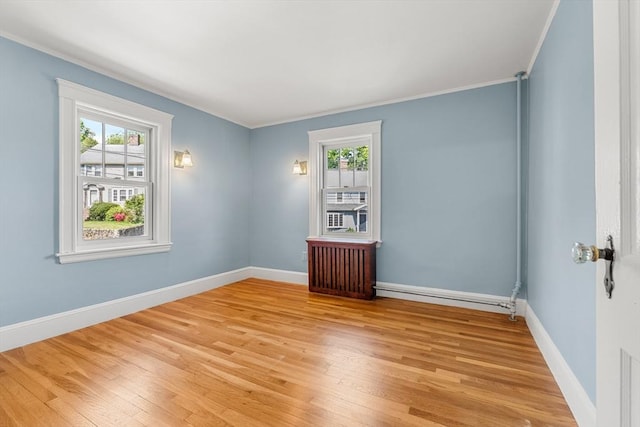 empty room featuring light wood finished floors, crown molding, and baseboards