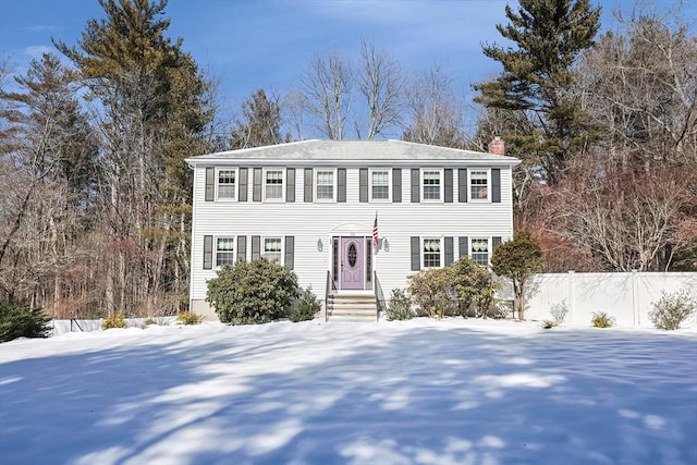 colonial-style house with a chimney and fence