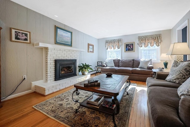 living room with light wood-type flooring, a fireplace, baseboards, and a baseboard radiator