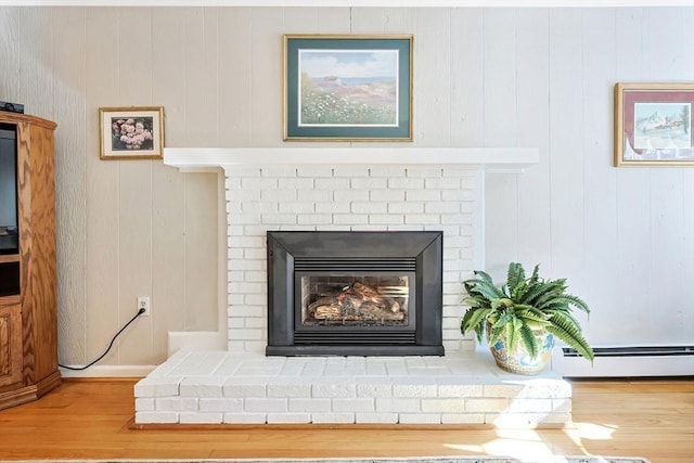 interior details featuring baseboard heating, a brick fireplace, and wood finished floors