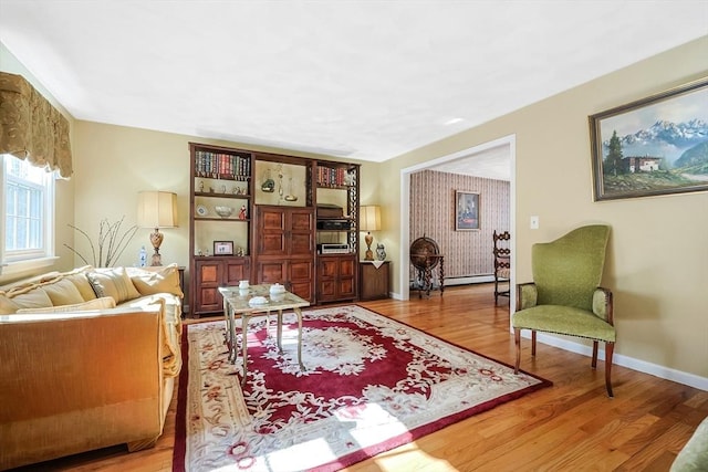 living room featuring a baseboard radiator, light wood-style flooring, and baseboards