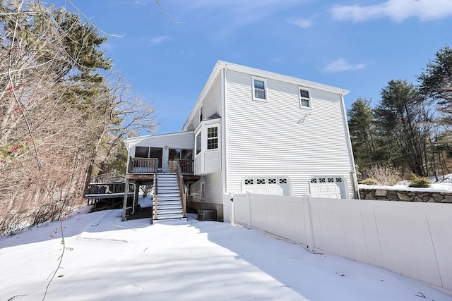 exterior space with stairway, an attached garage, fence, and a sunroom