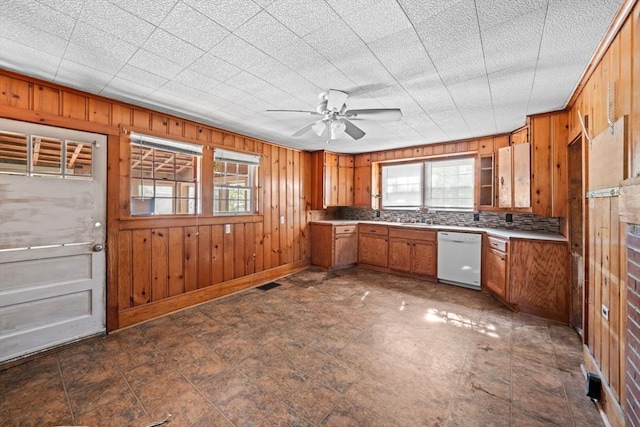 62 County St, Taunton, MA 02780 - kitchen with dishwasher, brown cabinetry, wood walls, ceiling fan, and baseboards