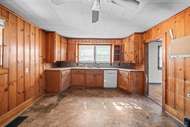 62 County St, Taunton, MA 02780 - kitchen featuring white dishwasher, brown cabinetry, wooden walls, a ceiling fan, and light countertops