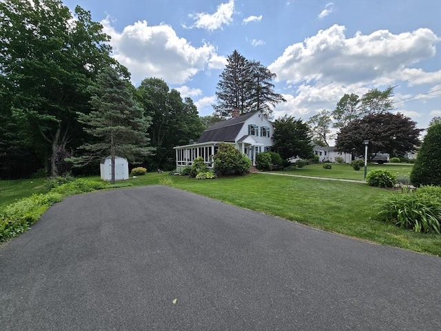 38 N W St, Agawam, MA 01030 - view of front of house featuring a shed, a front yard, driveway, and a chimney