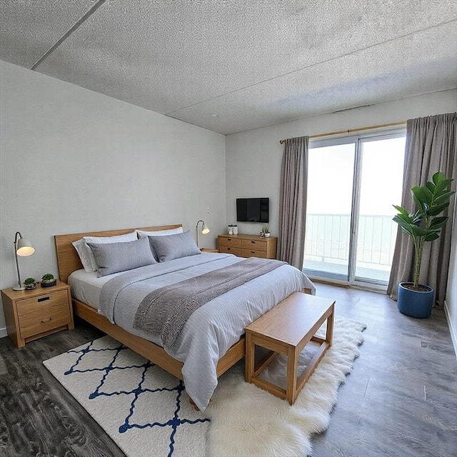 bedroom featuring access to outside, a textured ceiling, and wood finished floors