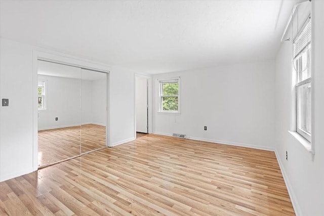 unfurnished bedroom with light wood-type flooring, baseboards, and a closet