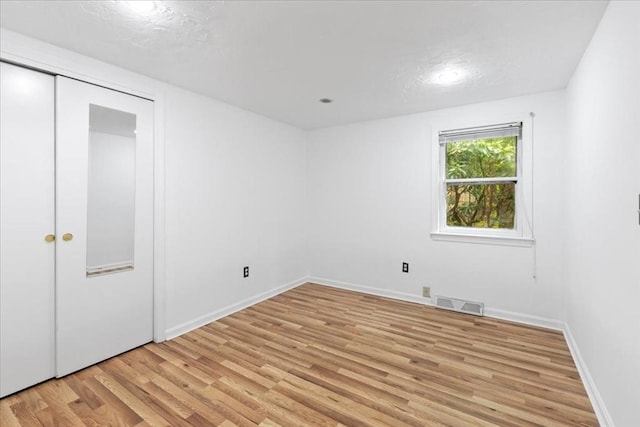 unfurnished bedroom featuring light wood-style flooring, baseboards, and a closet