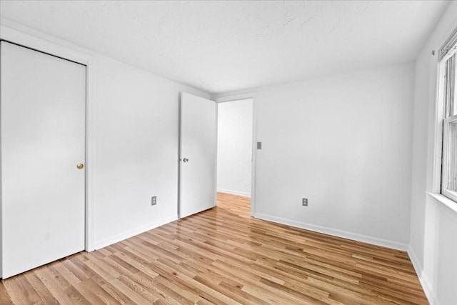 unfurnished bedroom with light wood-style floors, baseboards, and a closet