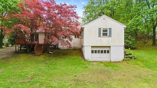 back of property with a deck, a yard, an attached garage, and driveway