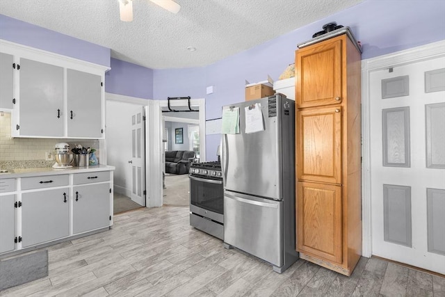 kitchen featuring decorative backsplash, stainless steel appliances, a textured ceiling, light countertops, and light wood-style floors