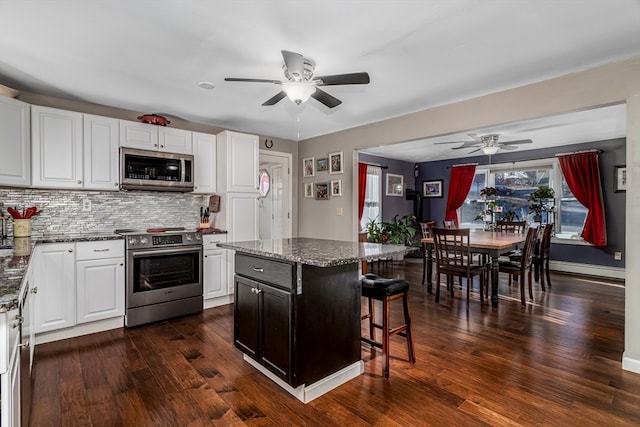 kitchen featuring appliances with stainless steel finishes, dark hardwood / wood-style floors, a kitchen island, and white cabinetry