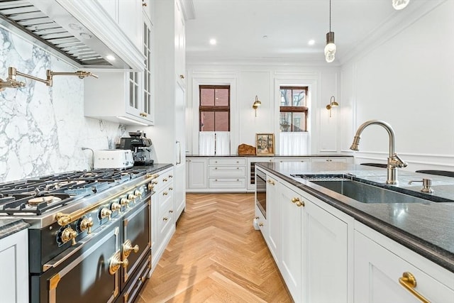 kitchen with custom range hood, a sink, backsplash, gas stove, and crown molding