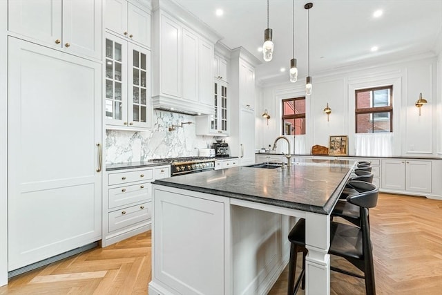 kitchen with backsplash, crown molding, a center island with sink, a breakfast bar, and a sink