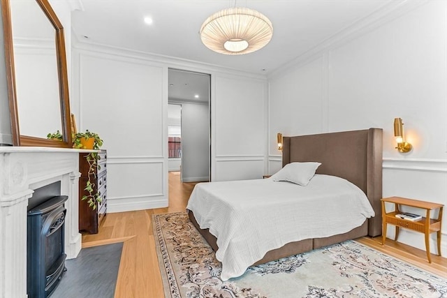 bedroom featuring wood finished floors, crown molding, and a decorative wall