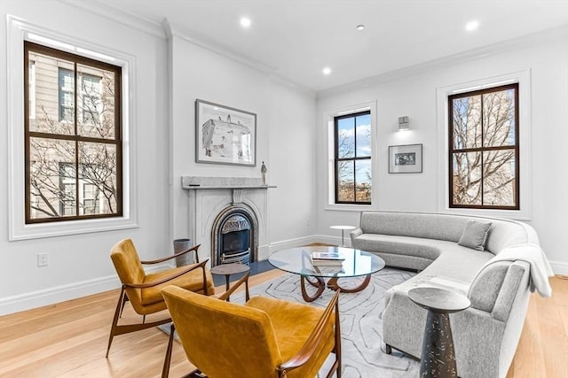 living area with light wood-type flooring, baseboards, and ornamental molding