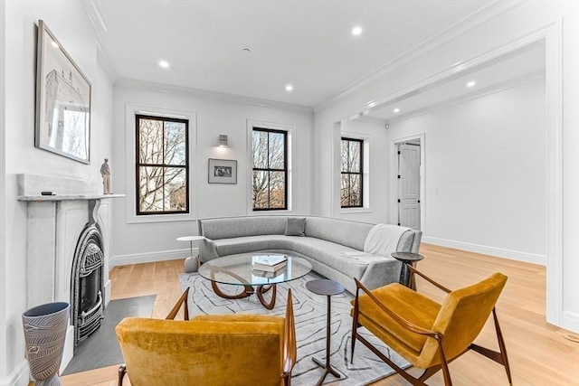 living room with crown molding, light wood-style flooring, a fireplace with flush hearth, and baseboards