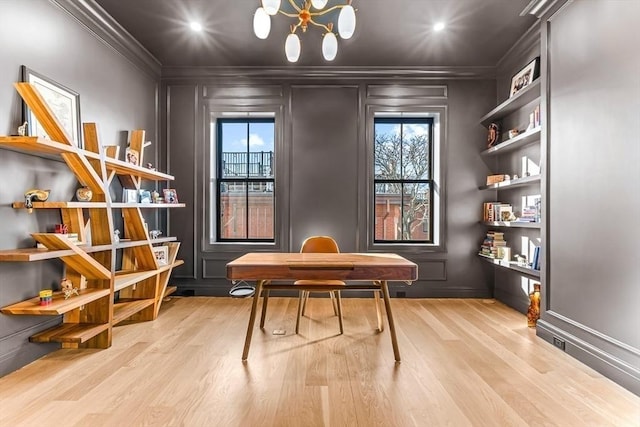 home office featuring built in shelves, wood finished floors, crown molding, and a decorative wall