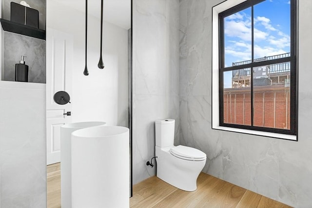 bathroom featuring toilet, wood finished floors, and a walk in shower