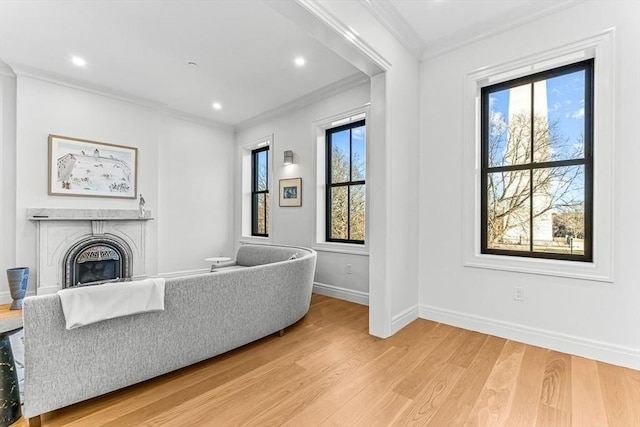 living room with a healthy amount of sunlight, ornamental molding, and light wood finished floors