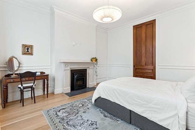 bedroom featuring a decorative wall, light wood-type flooring, and ornamental molding