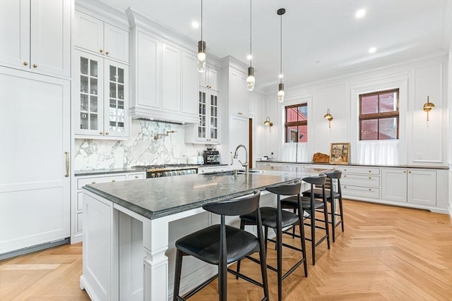 kitchen featuring a center island with sink, a sink, tasteful backsplash, a breakfast bar area, and range