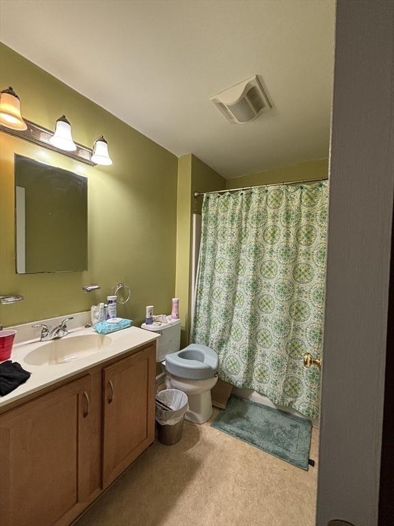 bathroom featuring vanity, toilet, and curtained shower