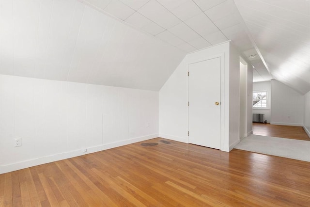 additional living space with lofted ceiling, radiator, and wood-type flooring