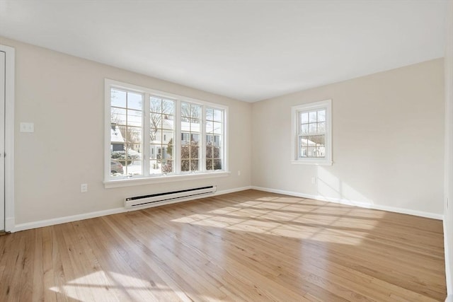 unfurnished room with a baseboard heating unit and light hardwood / wood-style floors