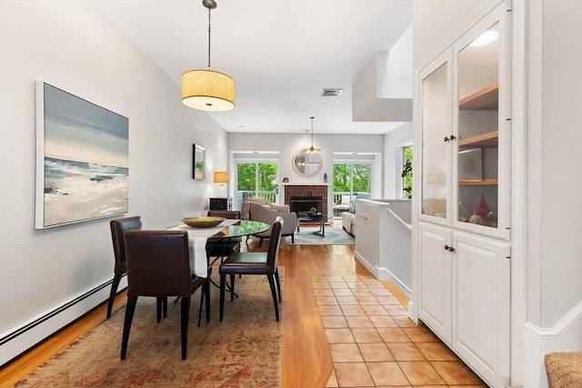 64 Prospect St Unit B, Marblehead, MA 01945 - dining space with a baseboard heating unit, light wood finished floors, and a brick fireplace